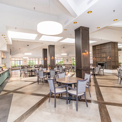 A spacious and modern restaurant dining area with tables and chairs arranged neatly under bright lighting.