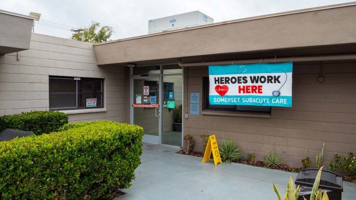 Entrance to a healthcare facility with a 'Heroes Work Here' banner displayed.