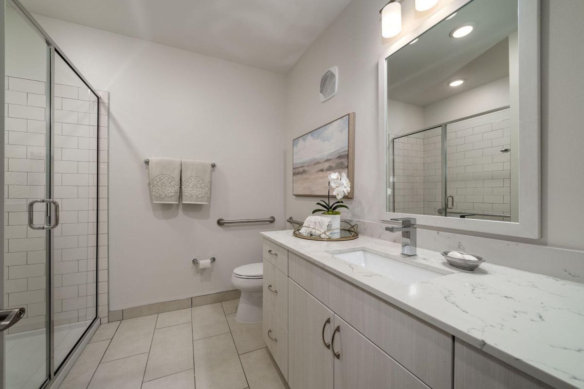 A modern bathroom with a large mirror, white cabinetry, and neatly arranged towels.
