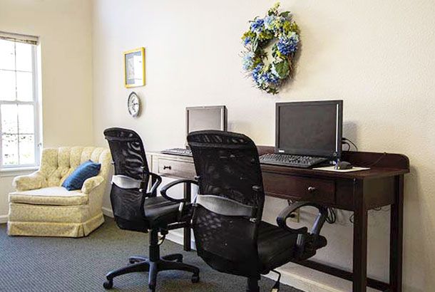 A small office space with two computer workstations, ergonomic chairs, and a decorative wreath on the wall.