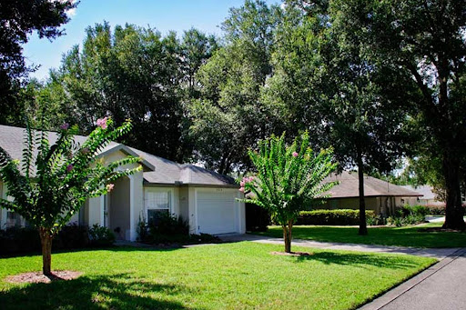 A beautiful home surrounded by lush greenery and a well-maintained lawn.