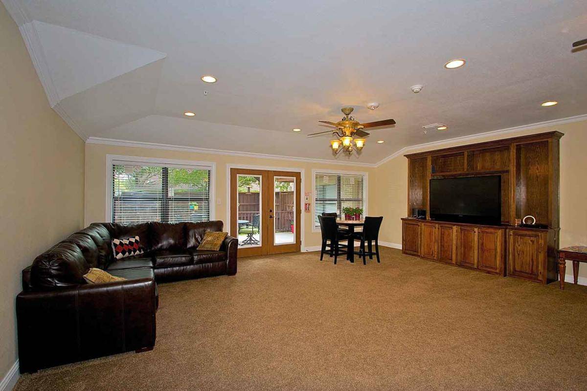 Spacious living room with a couch, table, ceiling fan, and large windows.