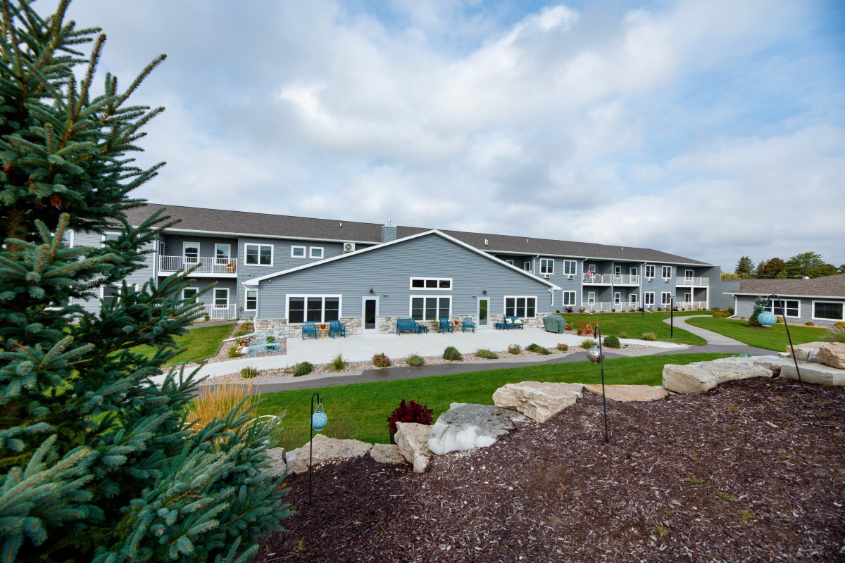 A modern residential apartment complex with landscaped gardens under a cloudy sky.