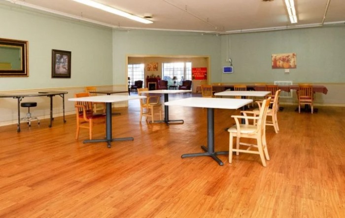A spacious indoor dining area with tables and chairs on a wooden floor.