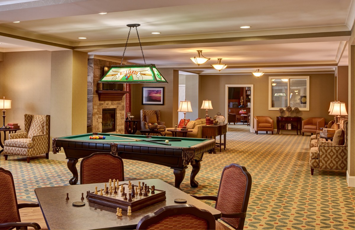 A cozy game room featuring a billiards table, chess board, and comfortable seating.