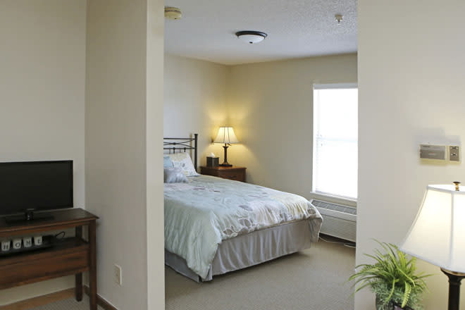 A cozy bedroom with a bed, lamp, and window.