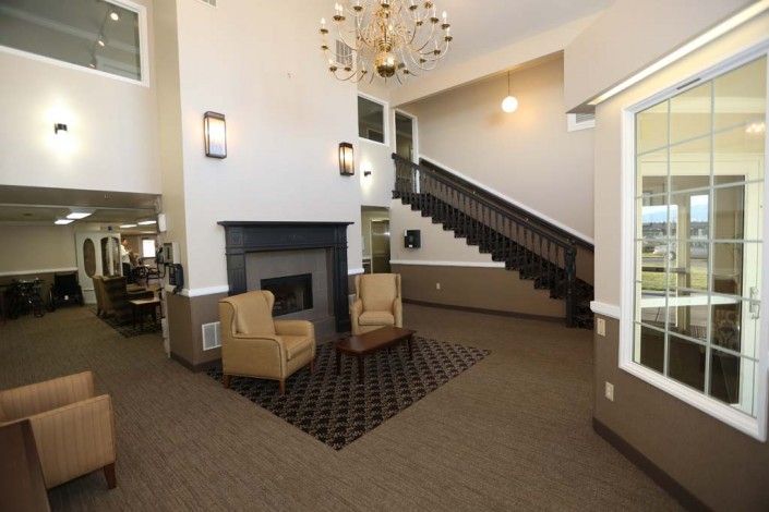 A cozy lobby area featuring a fireplace, two armchairs, and a staircase.