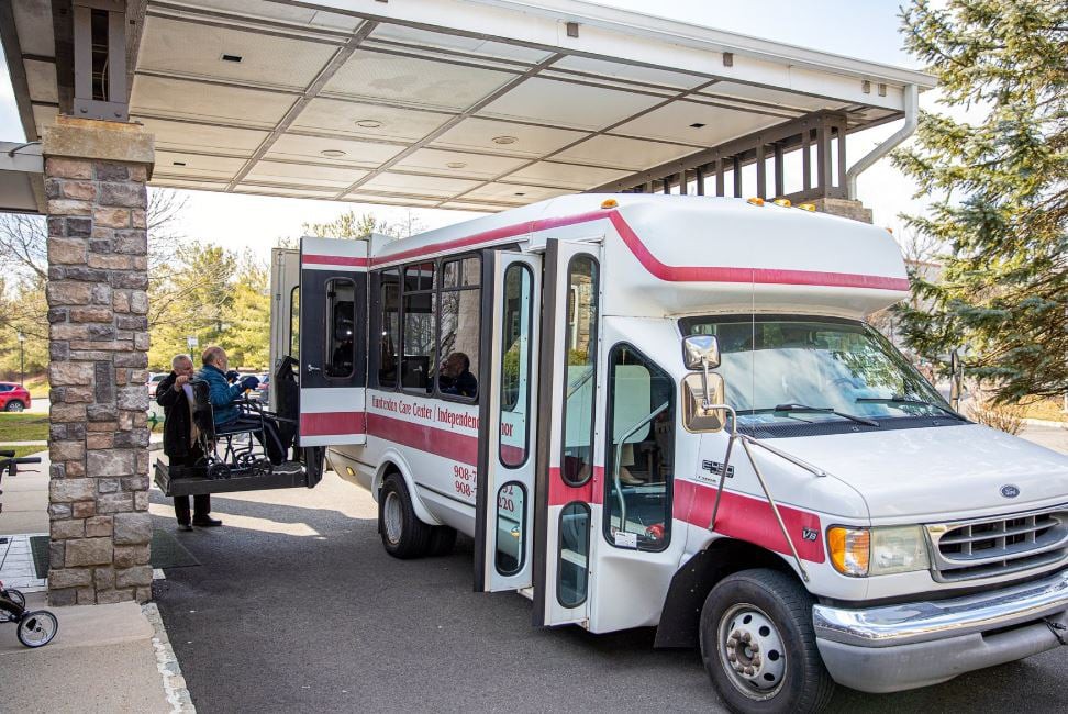A bus equipped with a wheelchair lift is parked under a covered area, facilitating accessibility for passengers.