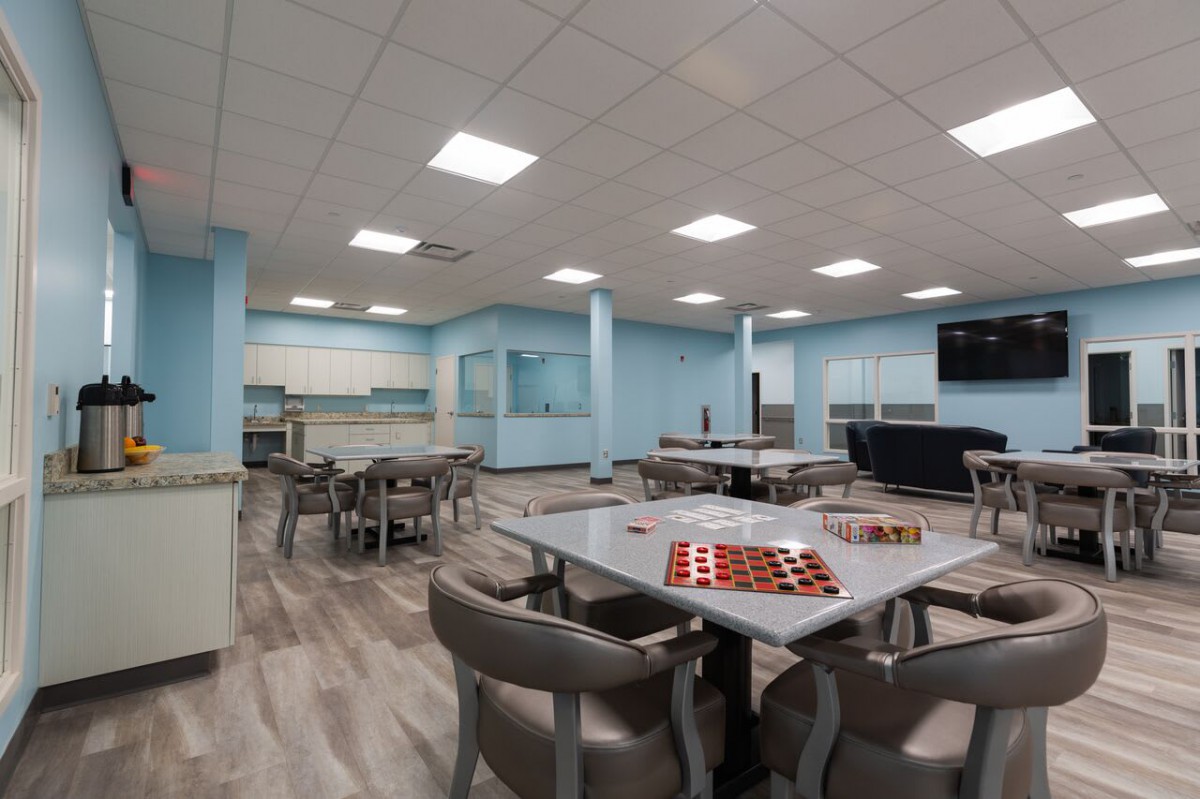 A modern multi-purpose room with tables, chairs, and games.