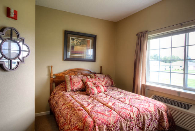 Cozy bedroom with a decorative bedspread and window view.