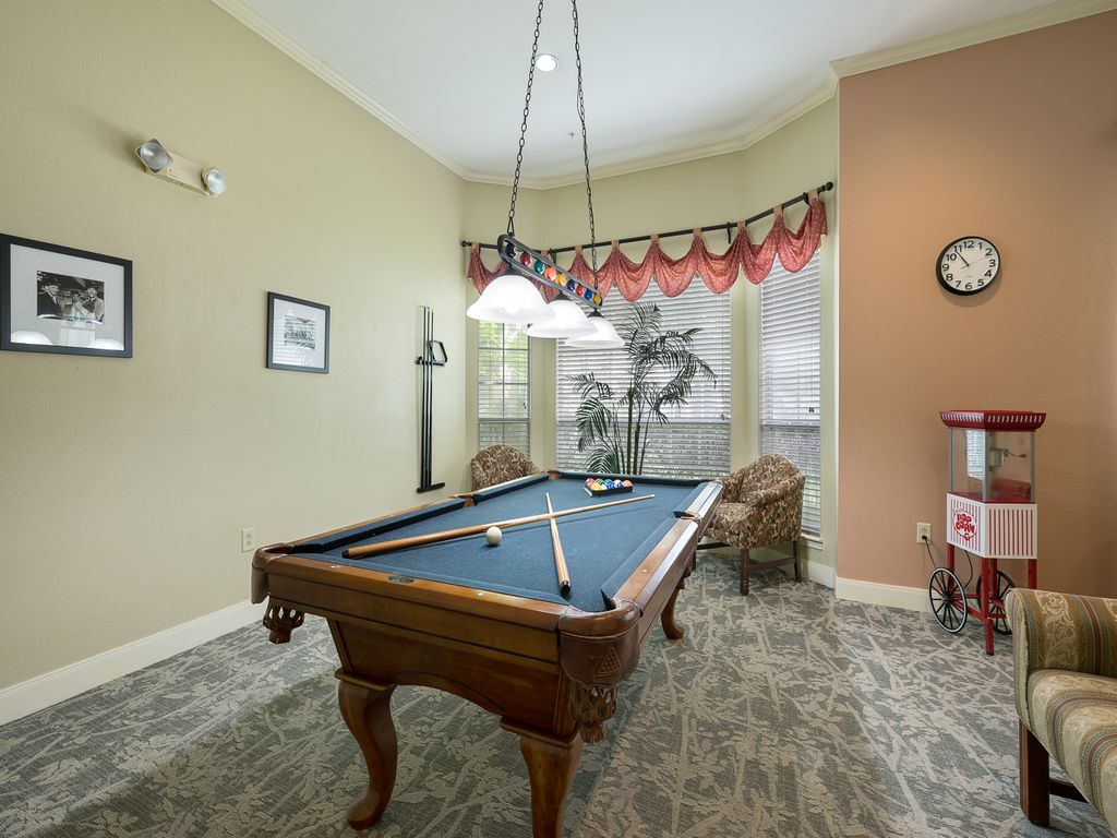 A well-lit game room featuring a billiard table with cues and balls ready for play.
