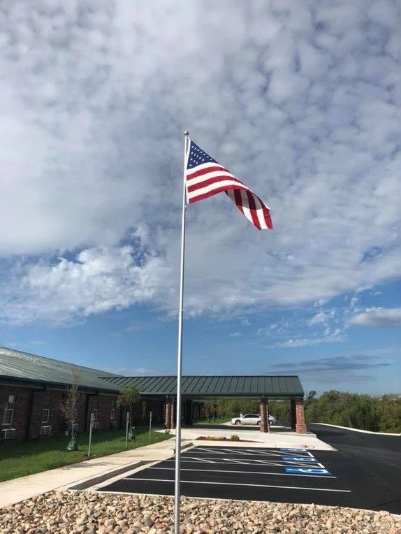 An American flag waving on a flagpole in front of a building under a cloudy sky.