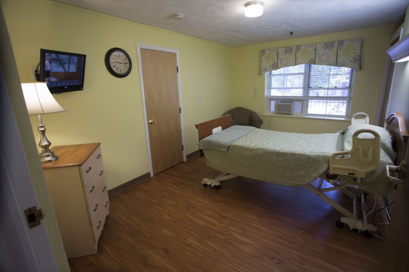 A simple hospital room with a single bed, TV, and window.