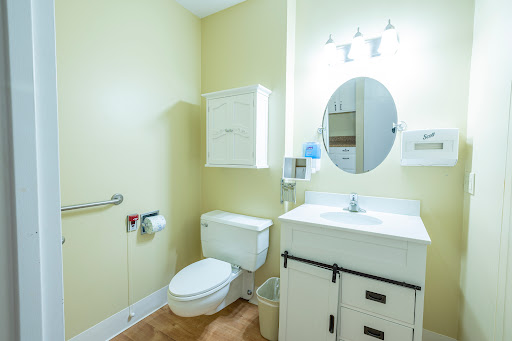 A clean and simple bathroom featuring a toilet, sink with mirror, and light fixtures.