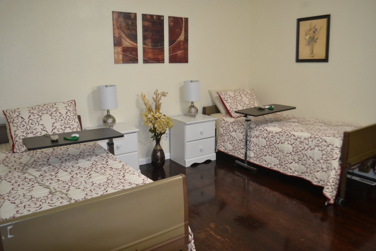 A cozy bedroom with two beds, each adorned with floral bedding and complemented by matching nightstands and lamps.