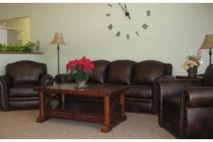 A cozy living room with leather furniture, a wooden coffee table adorned with poinsettias, and a wall clock for decoration.