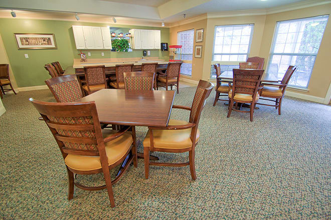 A spacious dining area with wooden tables and chairs adjacent to a kitchen.