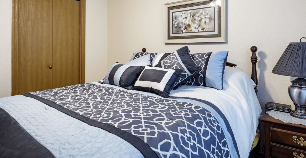 A neatly made bed with patterned bedding and decorative pillows in a cozy bedroom.