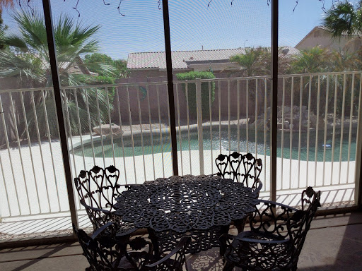 A serene view from a screened patio showcasing an intricately designed table and chairs overlooking a pool.