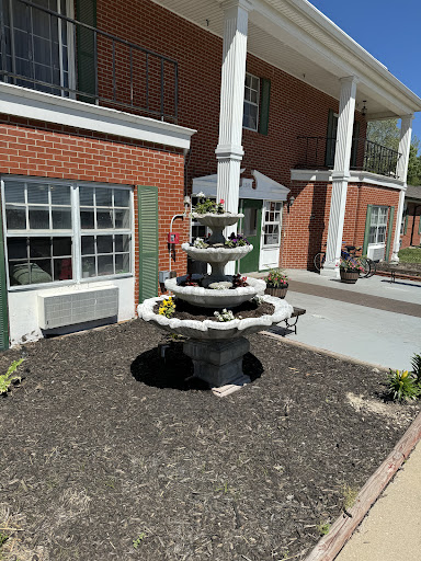 A charming multi-tiered fountain surrounded by a landscaped garden at an outdoor setting.
