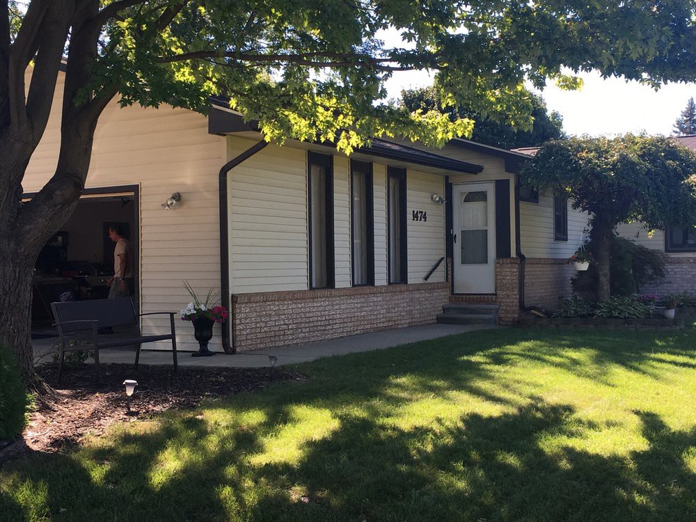 A suburban house with a well-maintained yard and trees casting shadows in the daytime.