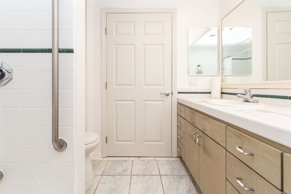 A clean, modern bathroom with a large mirror and wooden cabinets.