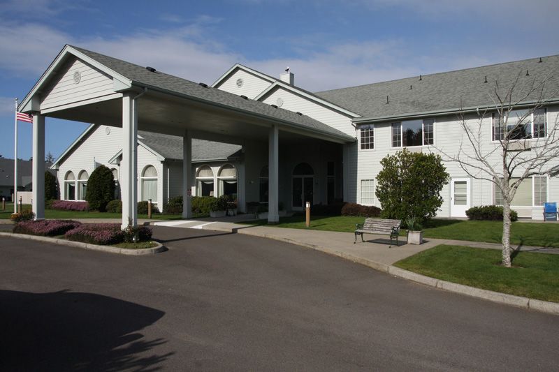 A large building with a covered entrance and landscaped surroundings.