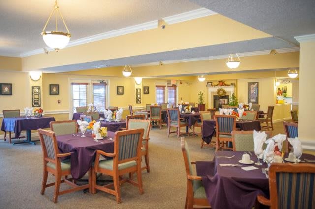 A spacious dining area with neatly arranged tables and chairs, featuring warm lighting and elegant decor.