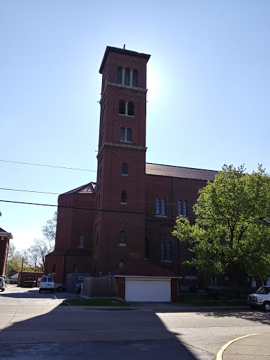 A brick church with a tall tower, illuminated by sunlight.