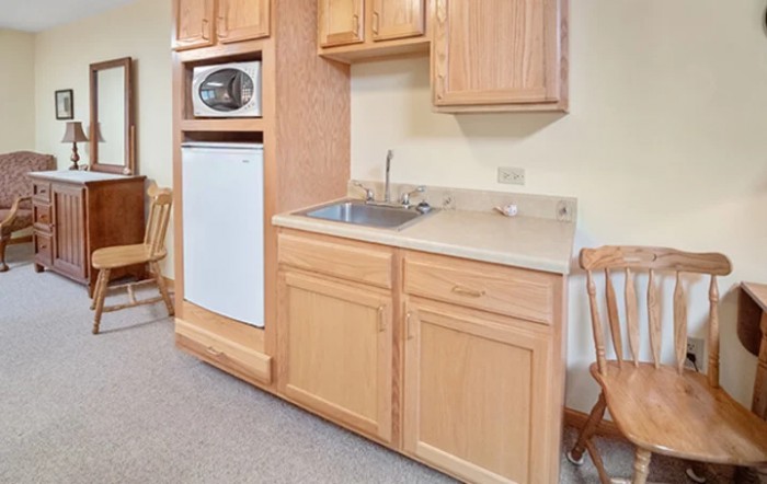 A compact kitchen area featuring wooden cabinets, a sink, a microwave, and a refrigerator.