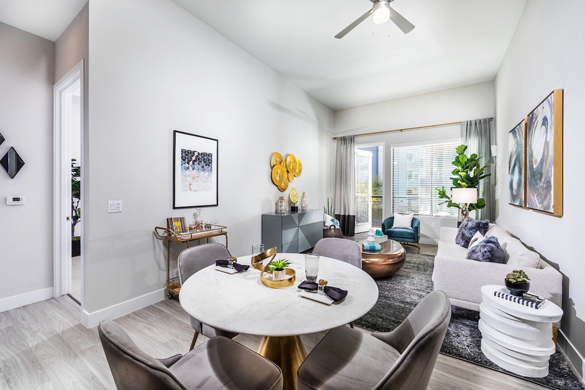 A modern living and dining area with stylish furniture, art pieces, and lush greenery.
