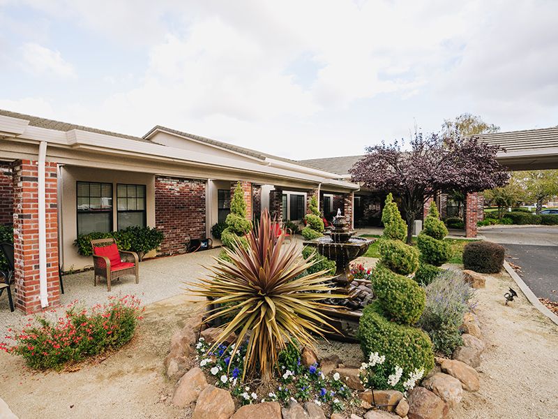 A beautifully landscaped garden with a central fountain in front of a house.