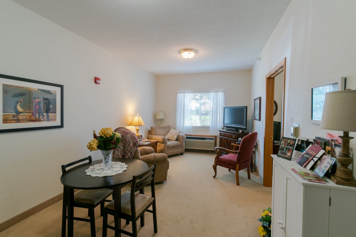 Cozy living room with a small dining area, armchairs, and a television.