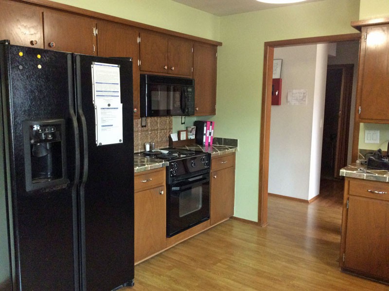 A cozy kitchen with wooden cabinets and modern appliances, including a black refrigerator, oven, and microwave.