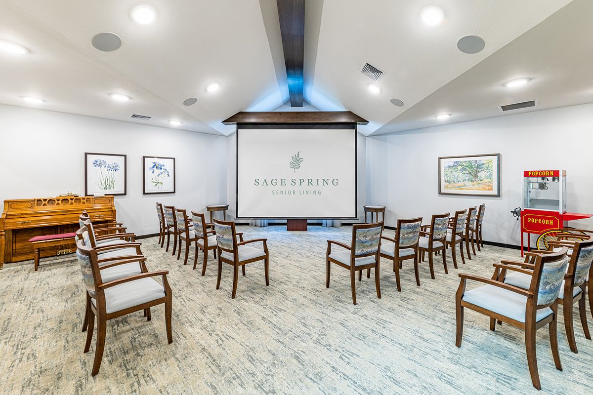 A well-lit conference room with a projector screen and arranged chairs for a meeting.