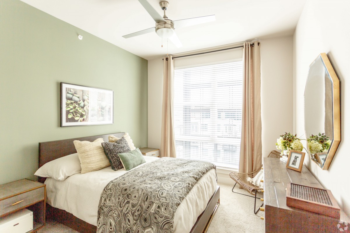 A cozy and modern bedroom filled with natural light, featuring a neatly made bed, elegant decor, and a soothing color palette.