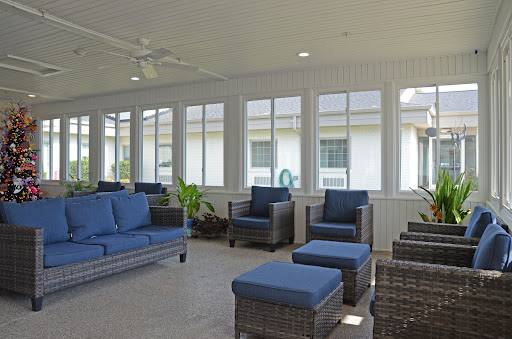 A bright and inviting sunroom featuring comfortable seating with blue cushions and large windows for natural light.