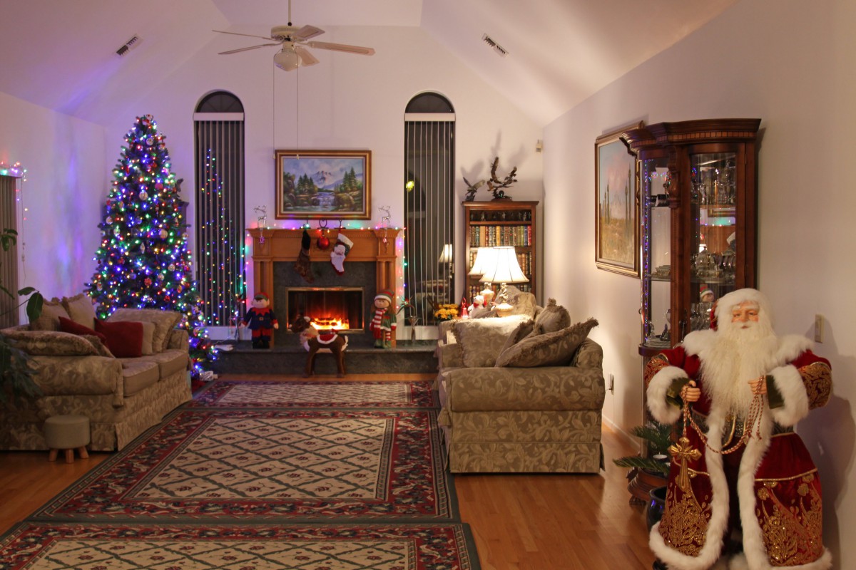 A cozy living room decorated for the Christmas season with a beautifully lit tree and a warm fireplace.