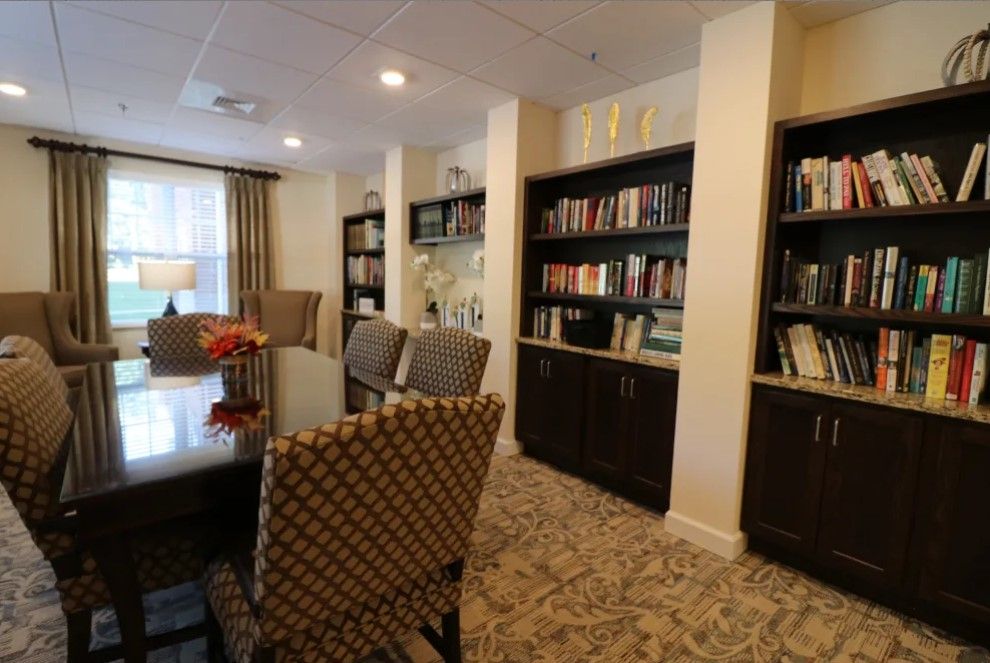 A cozy library space with bookshelves, a table, and chairs for reading.