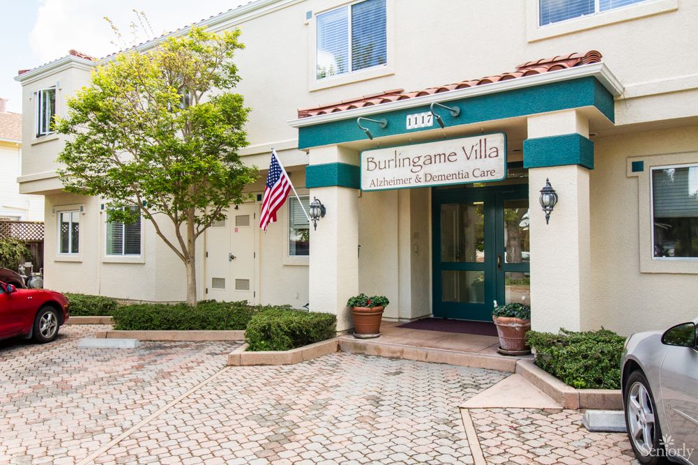 Entrance to a building with a sign, American flag, and potted plants.