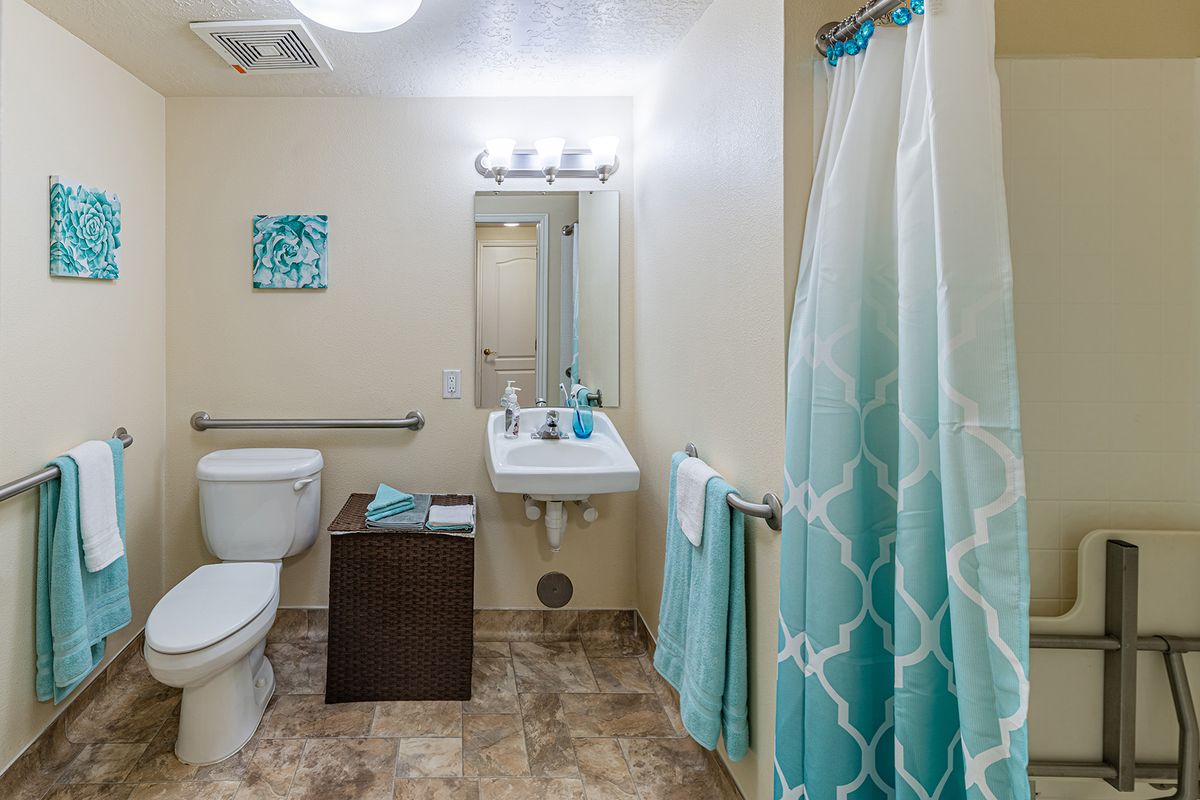 A well-organized bathroom with teal accents and modern fixtures.