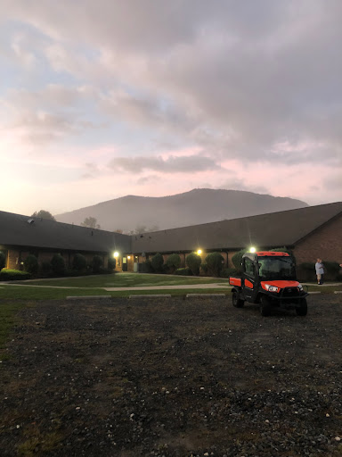 A serene evening view of a building with mountains in the background and a tractor parked nearby.
