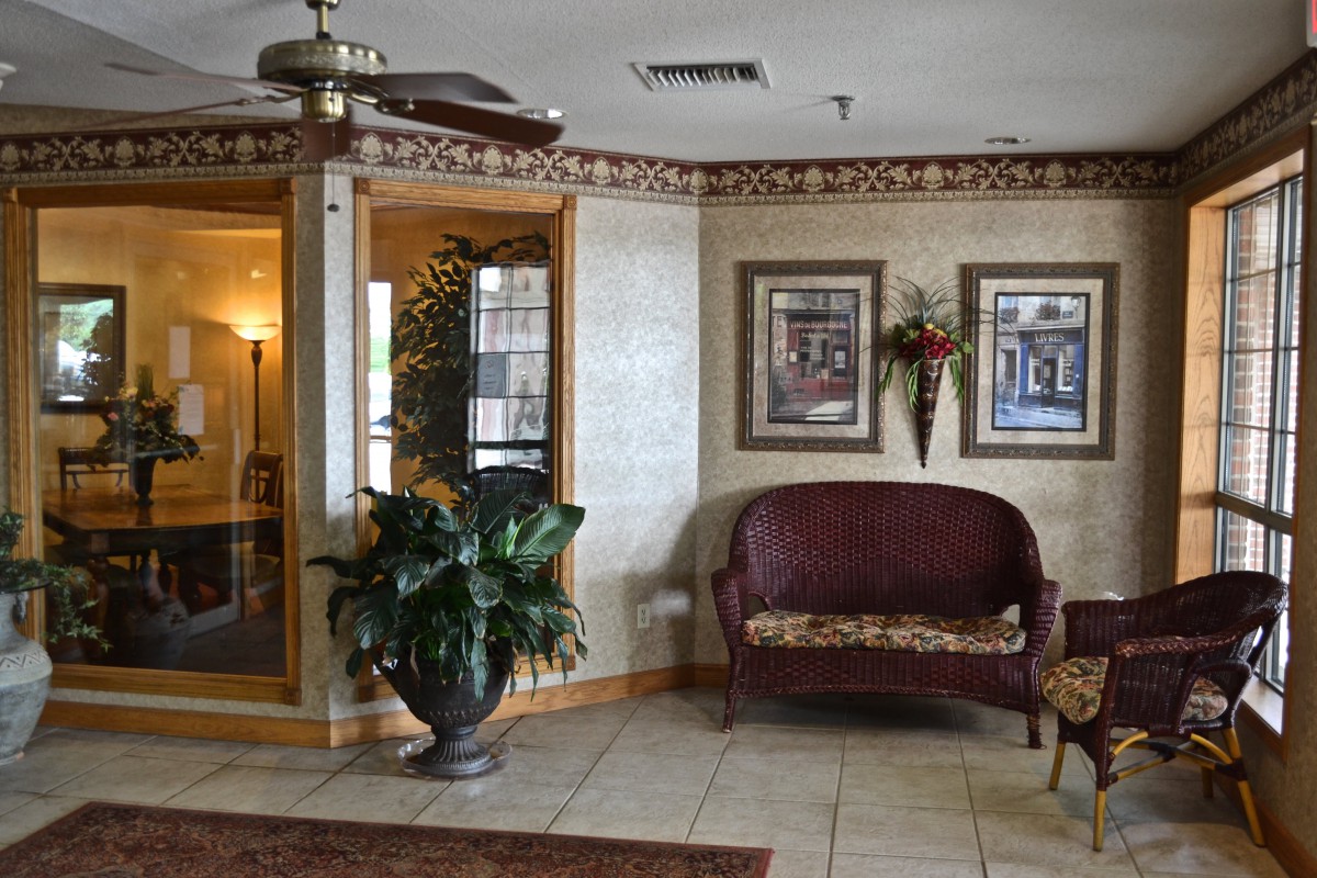 A cozy lobby area featuring a sofa, potted plants, and framed artwork on the walls.
