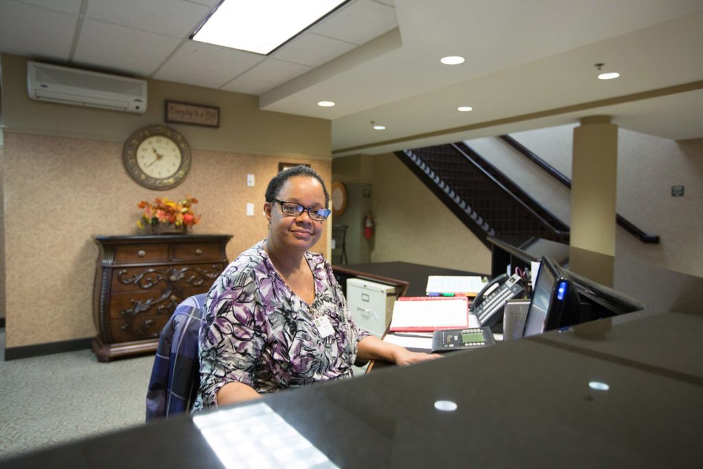 A person sitting at a reception desk in an office setting.
