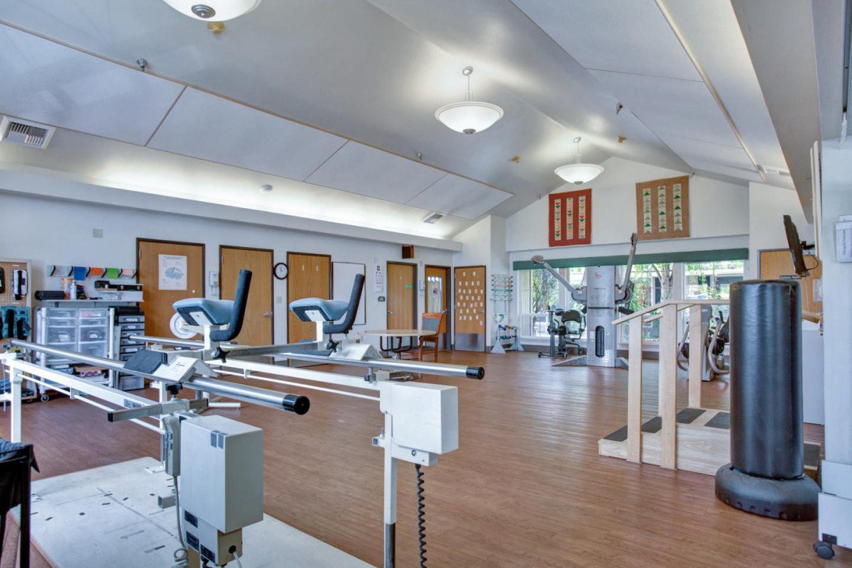 A spacious and well-lit gym with various exercise equipment.