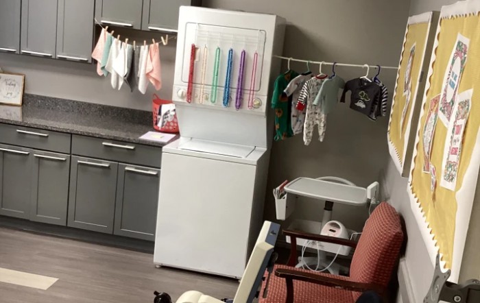 A laundry setup with clothes hanging to dry and a washing machine in a kitchen area.