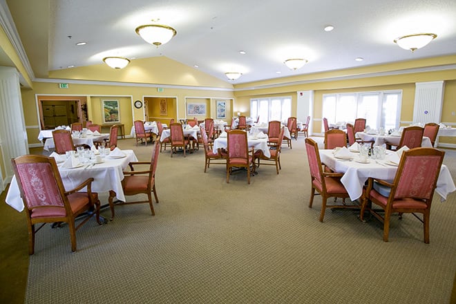 A spacious dining room with elegantly set tables and chairs, featuring a formal ambiance.