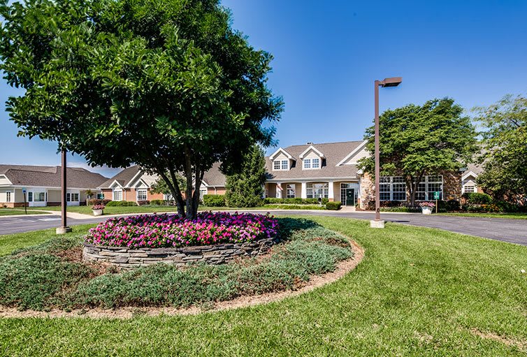 A beautifully landscaped residential building with a vibrant garden and a clear blue sky.