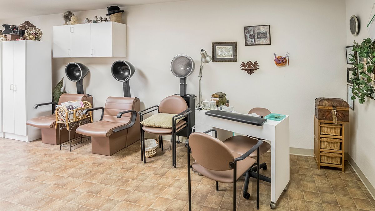 An empty beauty salon with hair dryers and a manicure station.