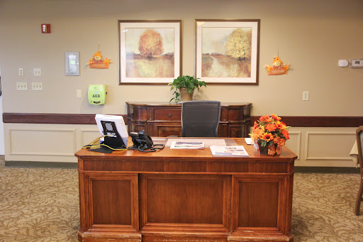 A warm and inviting office reception area featuring a wooden desk, decorative artwork, and floral arrangements.